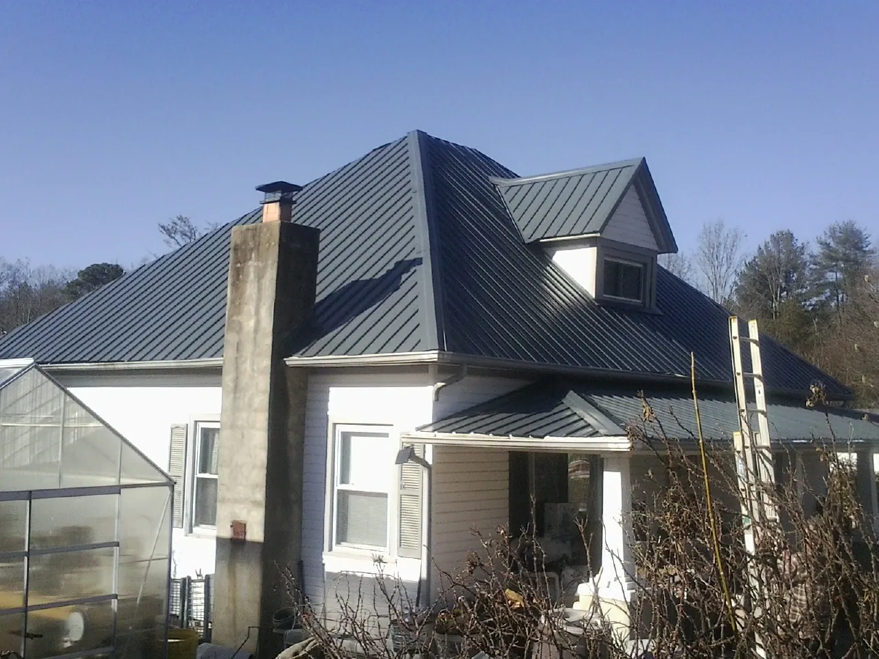 Dark blue standing seam metal roof on a white farmhouse with dormer — Slate & Tile Roof Repair by Roofing Brothers in Fordyce