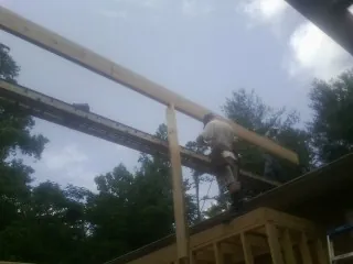 Carpenter setting a ridge beam over a new addition frame — Ice Dam Removal by Roofing Brothers in Fordyce