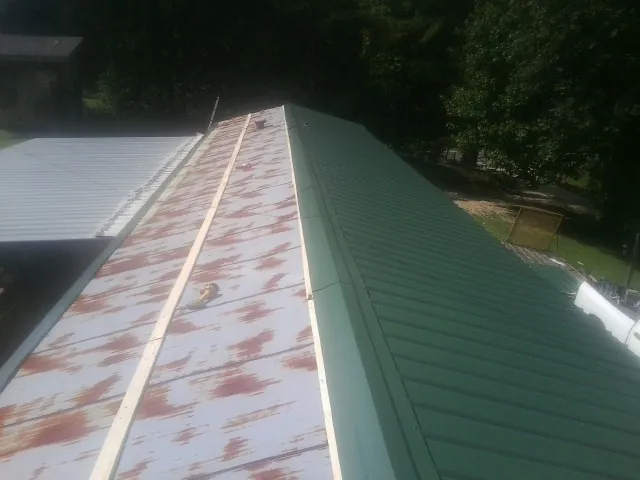 Old rusted panels beside newly installed green metal roofing — Wind Damage Roof Repair by Roofing Brothers in Fordyce