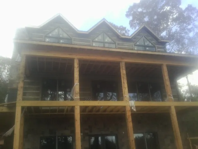 Dormers and porch framing on a large log home under construction — Roof Coating work by our crew in Fordyce