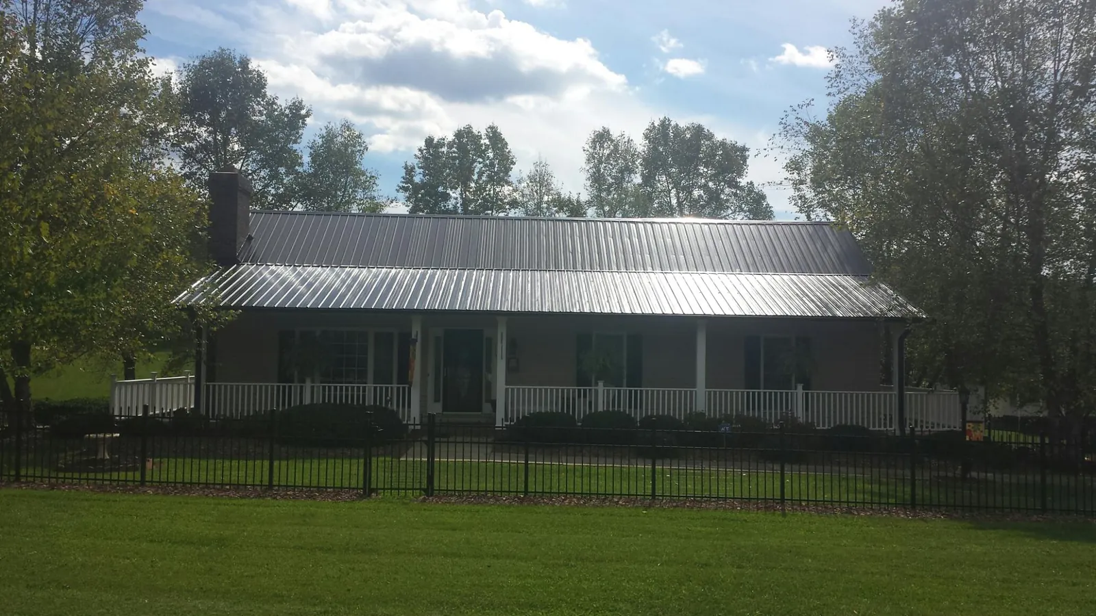 Gray metal roof on a brick ranch with a full width front porch — Gutter Guard Installation work by our crew in Fordyce