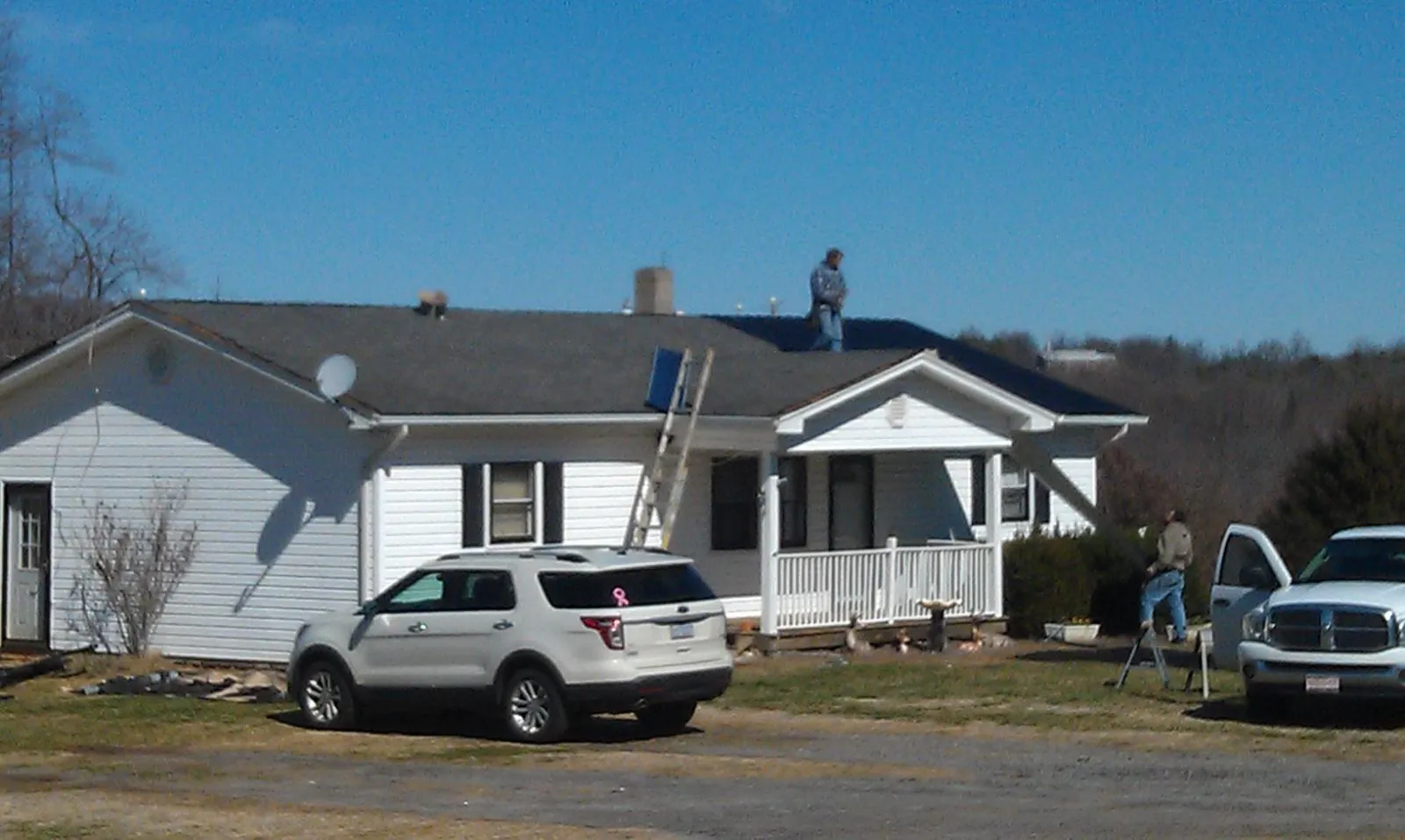 Roofers stripping shingles from a white ranch house roof in Fordyce