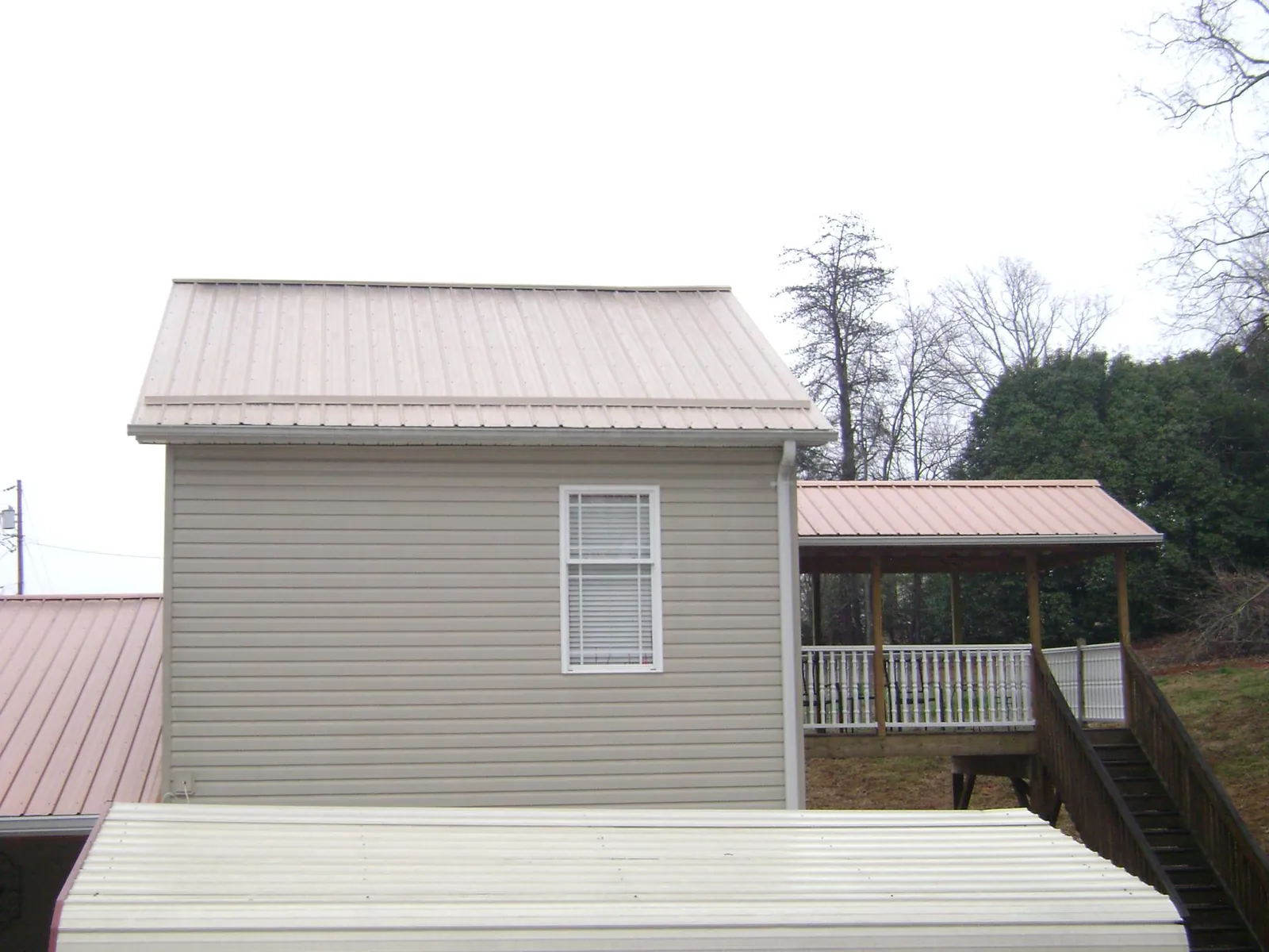 Tan metal roofs on a two story addition and attached porch, from a Roof Replacement job in Fordyce