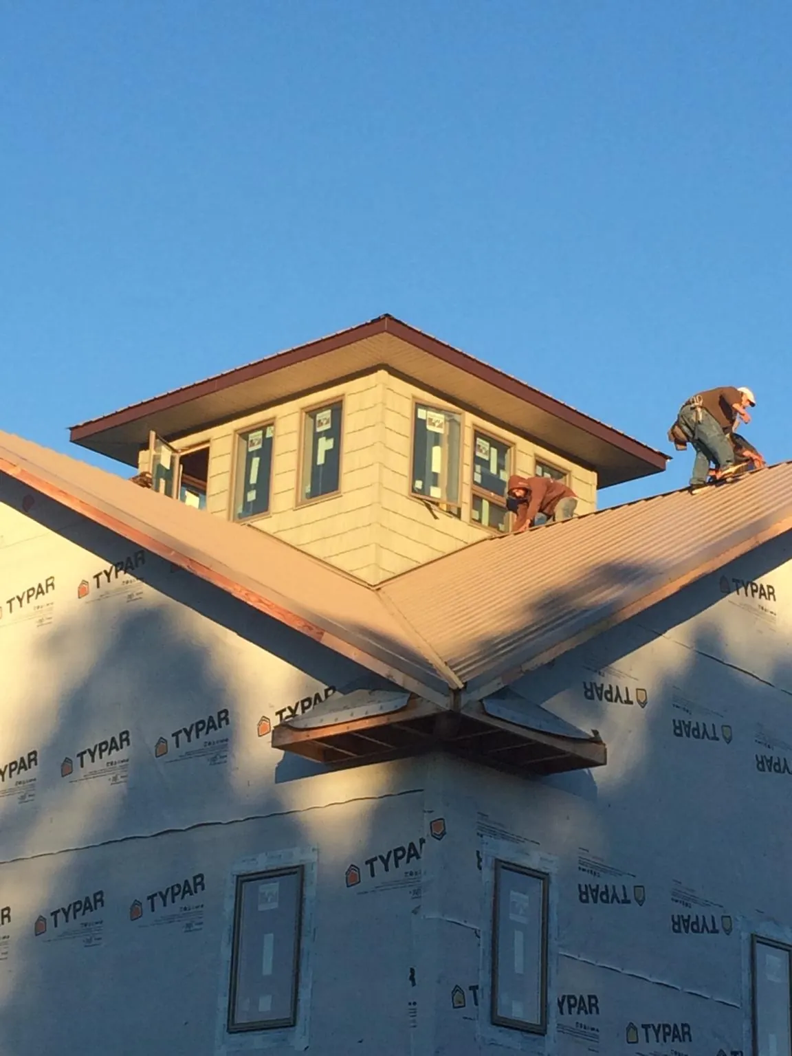 Roofers working around a rooftop cupola on a new metal roof at sunset — Roof Waterproofing in Fordyce by Roofing Brothers